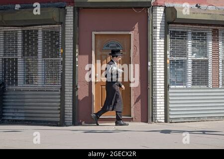 A young orthodox Jewish worshipper returns home from morning services. On Lee Avenue in Williamsburg, Brooklyn, New York Stock Photo