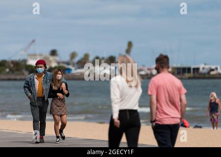 Melbourne, Australia, 18 October, 2020. A couple are seen walking by the beach during COVID-19 in St Kilda, Australia. Premier Daniel Andrews is under mounting pressure to ease restrictions in line with NSW, despite this, in his much anticipated press conference earlier on Sunday, the Premier only slightly lifted the worlds longest and strictest lockdown. Business saw no relief with only a hint of easing to come in two weeks. Credit: Dave Hewison/Speed Media/Alamy Live News Stock Photo