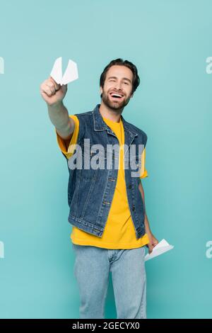 Smiling man holding paper planes isolated on blue Stock Photo