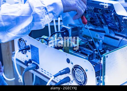 Hands of an Technician holding a screwdriver as he fixes an electronics device Stock Photo