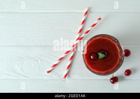 Glass of cherry smoothie, straws and ingredients on white wooden table Stock Photo