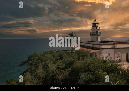 Dramatic colorful sunset at lighthouse Calella in Catalonia, Spain Stock Photo