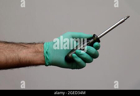 Male industrial worker hand wearing latex glove and holding screwdriver tool Stock Photo