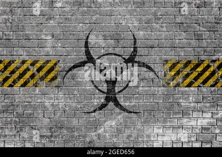 Faded biohazard sign with yellow-black lines on old brick wall with scratches and peeling paint Stock Photo