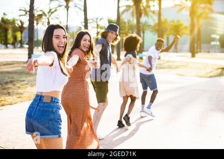 Multiethnic group of young friends running happily together  Stock Photo