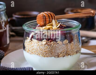 Granola with oatmeal, amaranth, roasted almonds, honey and yogurt in a glass bowl Stock Photo