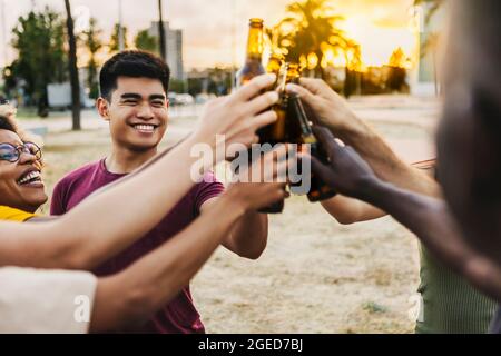 Multiracial friends celebrating and toasting beers at beach party Stock Photo