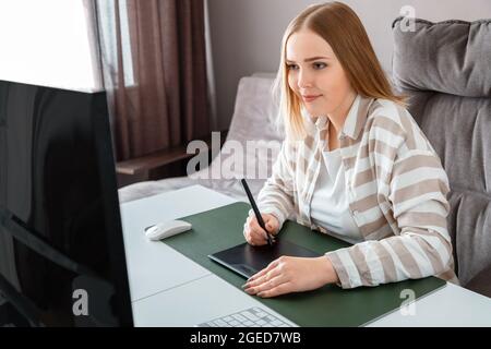Portrait of Young artist graphic designer During work. Caucasian blonde woman drawing on graphic tablet by Stylus pen using pc Computer at home office Stock Photo