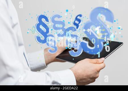 Digital illustration of floating law symbols and a binary code on a tablet in a businessman's hands Stock Photo
