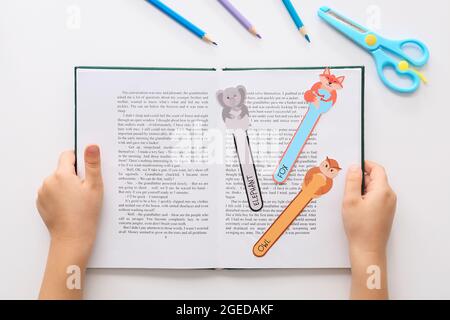 Little child with cute bookmarks reading book on white background Stock Photo