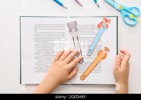 Little child with cute bookmarks reading book on white background Stock Photo