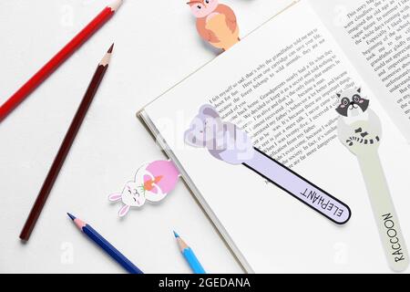 Cute bookmarks with book and pencils on white background Stock Photo
