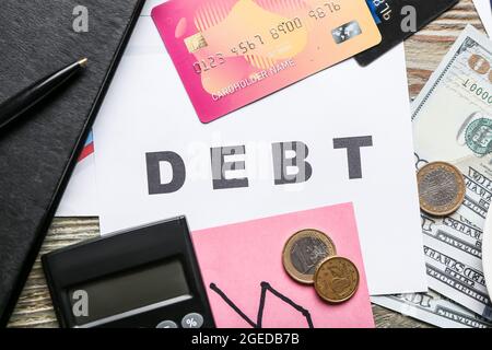 Word DEBT with money and calculator on wooden background Stock Photo