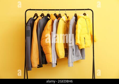 Rack with stylish clothes near color wall Stock Photo