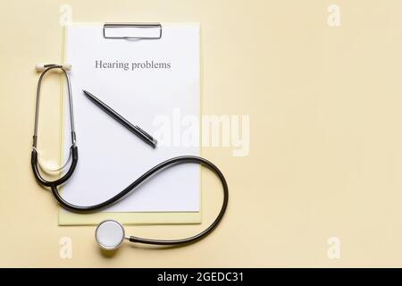 Clipboard with text HEARING PROBLEMS and stethoscope on color background Stock Photo