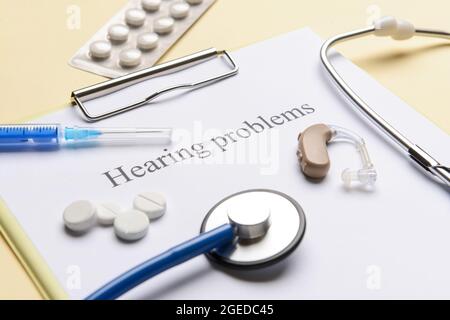 Clipboard with text HEARING PROBLEMS and pills on color background Stock Photo