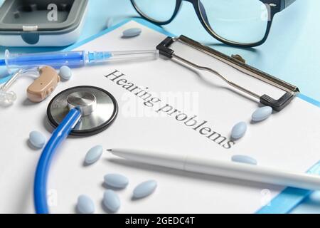 Clipboard with text HEARING PROBLEMS, stethoscope and pills on color background Stock Photo