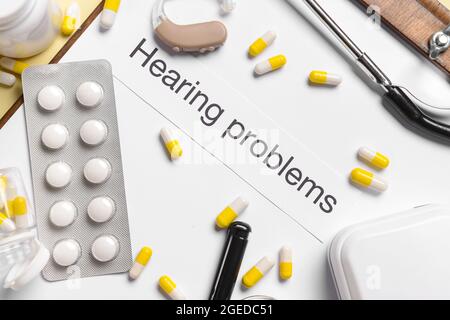 Clipboard with text HEARING PROBLEMS and pills on color background Stock Photo