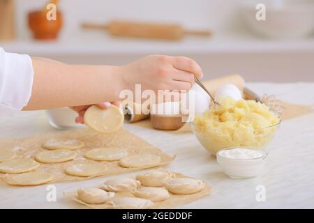 Woman preparing tasty dumplings on kitchen table Stock Photo