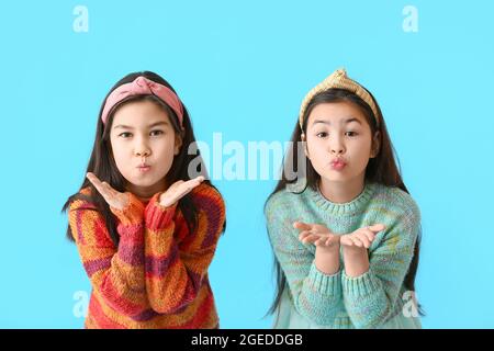 Cute little sisters blowing cheeks on color background Stock Photo