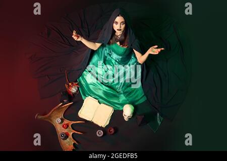 Young witch performing ritual on dark background Stock Photo