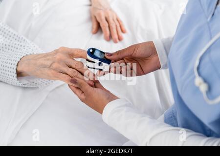 Cropped view of african american nurse fastening oximeter on finger of senior patient Stock Photo