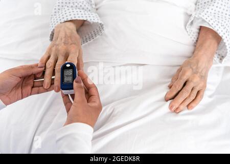 Top view of african american nurse fastening oximeter on hand of senior patient Stock Photo