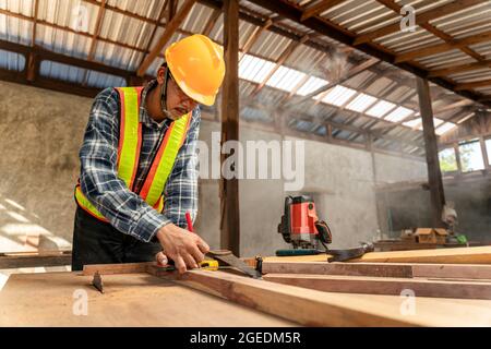 A male carpenter using pencil on a piece of wood on construction site Stock Photo