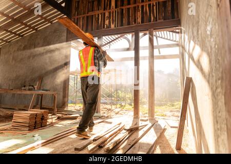 Carpenter holds wooden planks on construction site Stock Photo
