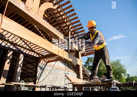 A male roofer carpenter working on roof structure on construction site Stock Photo