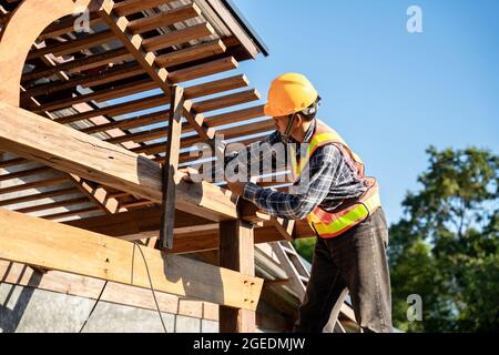 Roofer, A carpenter working on roof structure on construction site Stock Photo