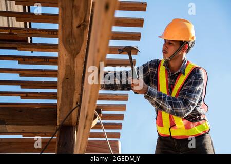 Asian roofer carpenter working on roof structure on construction site, Roofer Stock Photo