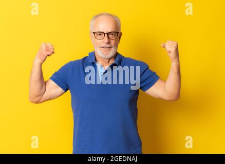 Big Luck. Excited mature man making winner gesture isolated over yellow wall, free space Stock Photo