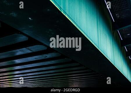 Colourful detail of the underside of a bridge showing a steel girder and beams. Stock Photo