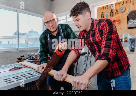 Senior carpenter teaching a younger man how to work Stock Photo