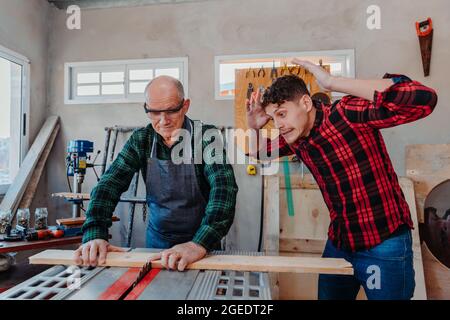Senior carpenter teaching a younger man how to work Stock Photo