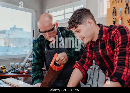 Senior carpenter teaching a younger man how to work Stock Photo