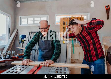 Senior carpenter teaching a younger man how to work Stock Photo