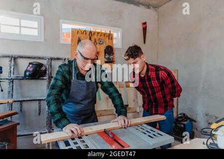 Senior carpenter teaching a younger man how to work Stock Photo