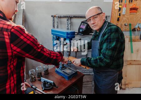 Senior carpenter teaching a younger man how to work Stock Photo