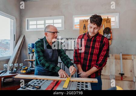 Senior carpenter teaching a younger man how to work Stock Photo