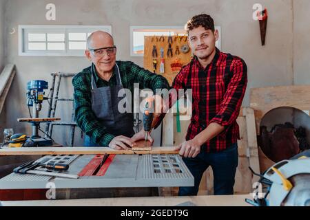 Senior carpenter teaching a younger man how to work Stock Photo