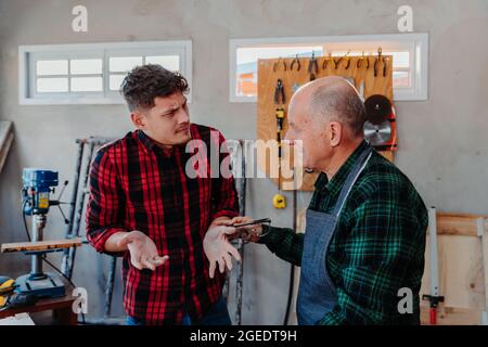 Senior carpenter teaching a younger man how to work Stock Photo