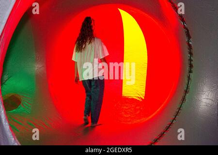 Architects of Air's touring structures in Blackburn, Lancashire, UK. 19th Aug 2021.  Zoe Felix, inside a giant balloon, explores the changing patterns of light, shifting as they pass through labyrinthine passages & cavernous domes. Dodecalis Luminarium provides moments of pause in meditative stillness and quiet wonder in the furthest corners of the precision-engineered, ‘hide and seek’ illuminated modular colour tunnels of light architecture. Stock Photo