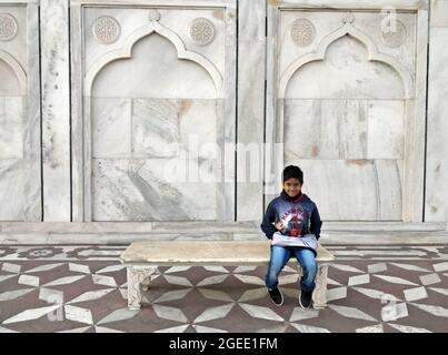 Agra, Delhi, India - 18 February 2018, Cute boy sitting on bench back side of taj mahal, Agra Delhi India Stock Photo