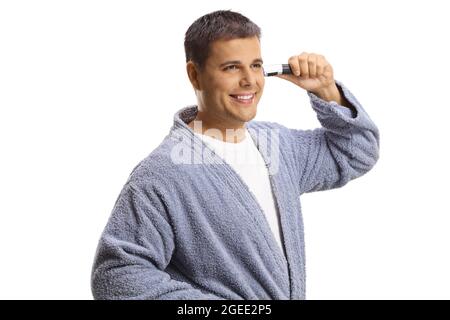 Young man in a bathrobe using an ear trimmer isolated on white background Stock Photo