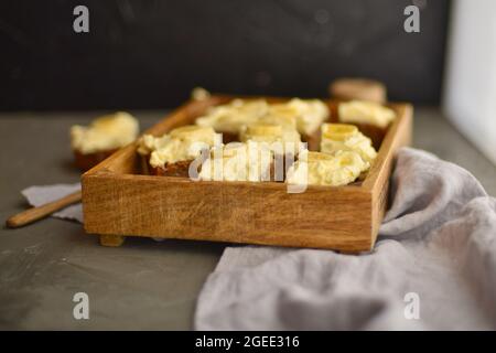 Tasty cake with banana with cream in wooden box. cheesecake on the table. sweet toffee cake. Stock Photo