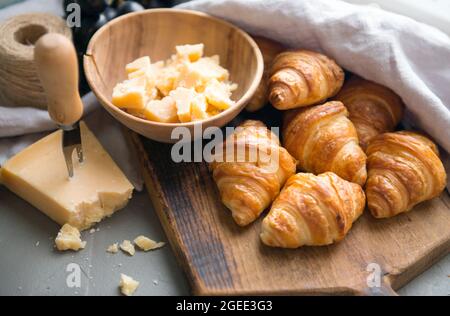 Croissants whit delicious cheese and grapes for tasty breakfast. Original tasty French croissants with cheese and on the wooden table. Stock Photo
