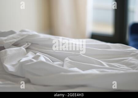 Unmade bed with crumpled bed sheet. Shallow depth of field Stock Photo