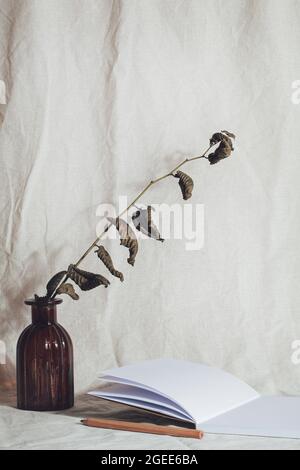 workplace with notebook, pencil, dried flower on linen textile. Kinfolk designed interior. minimal, stylish concept. new trendy home decor. Stock Photo